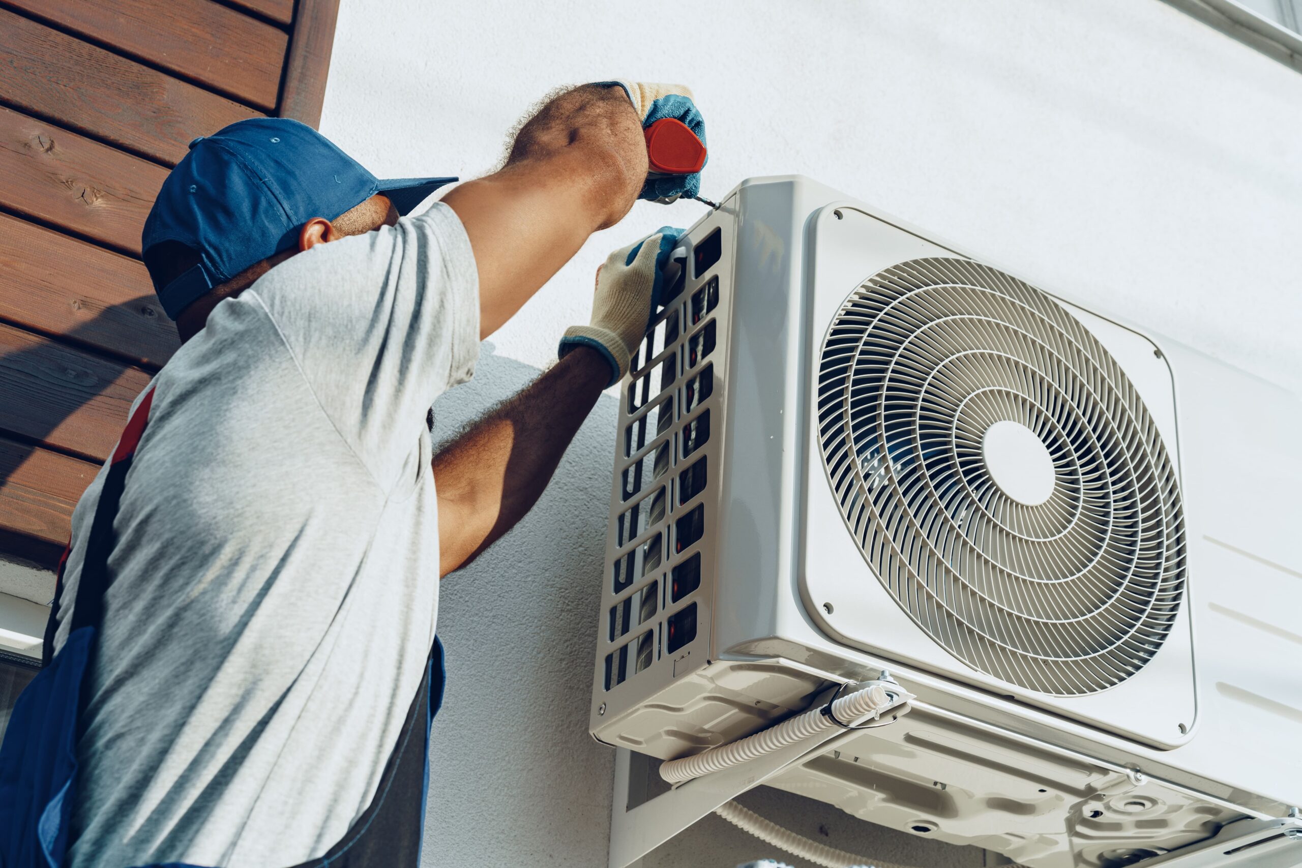 A friendly technician in a uniform shaking hands with a homeowner in front of an air conditioner unit