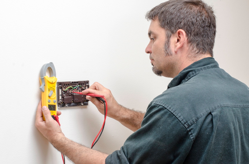 Miami, FL: Technician adjusting a programmable thermostat with a multimeter. Expert service for optimal home climate control and energy savings.